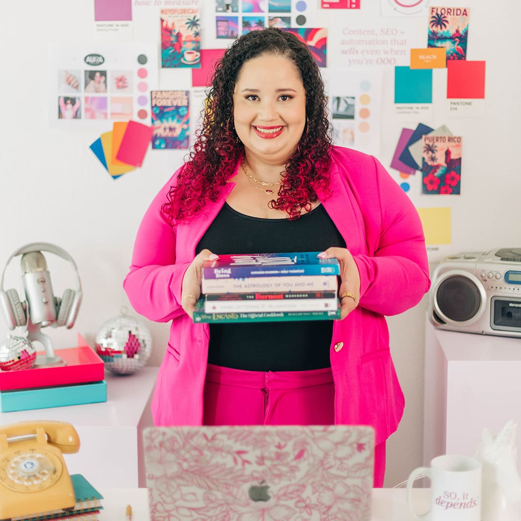 Kristine Gonzalez smiling and holding an iPad, standing in a colorful office space with books, phone, and a cafecito mug in the background.