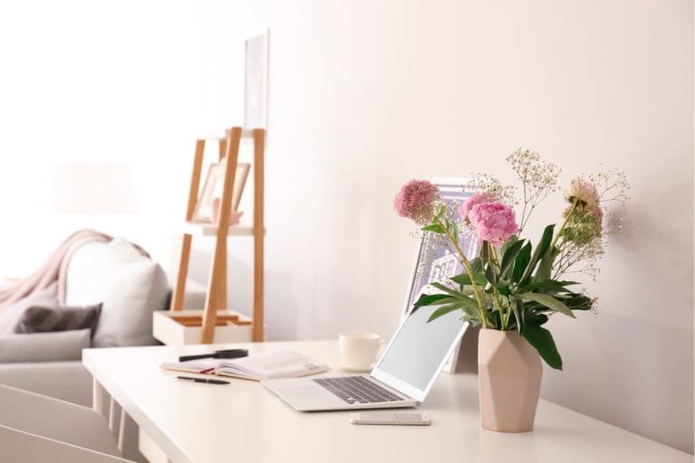 Modern minimalist desk with laptop, notebook and flowers, symbolizing clarity, trust and the psychology of decision making in website conversions.